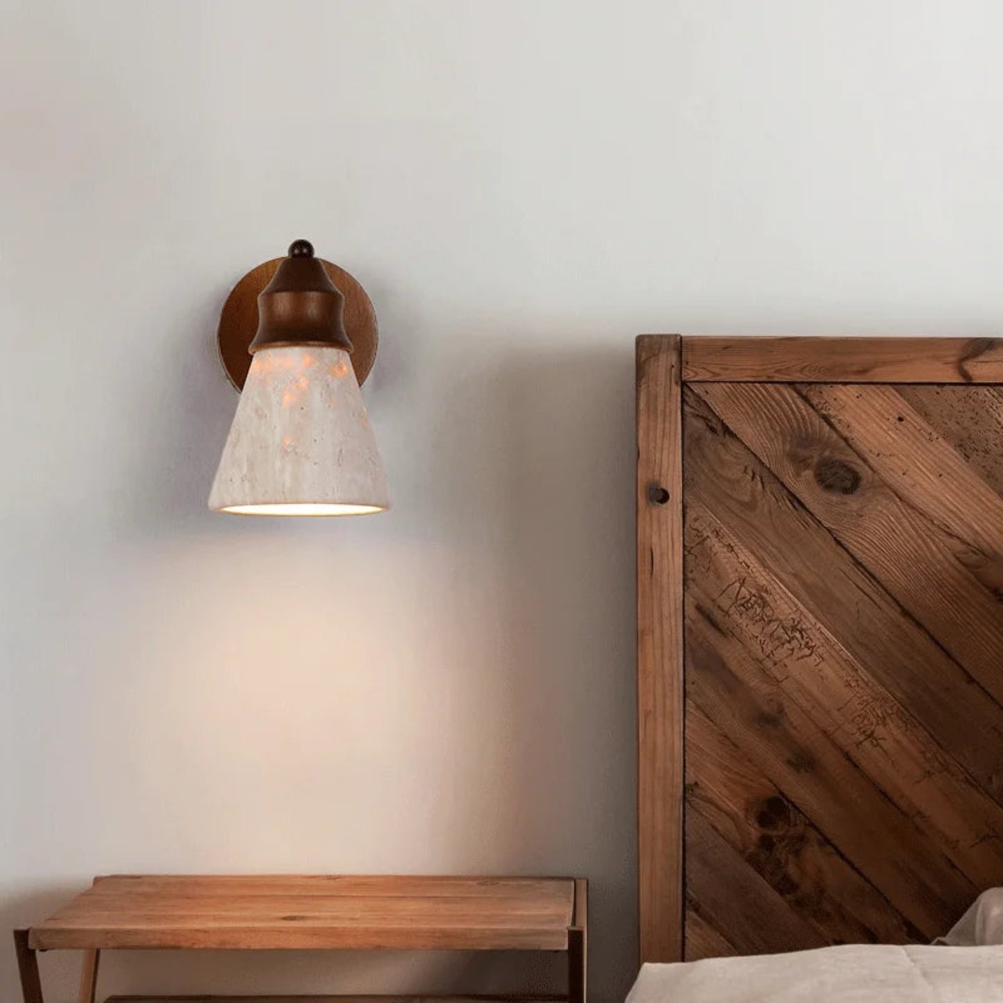 Wall sconce with a wooden headboard and nightstand in a room setting