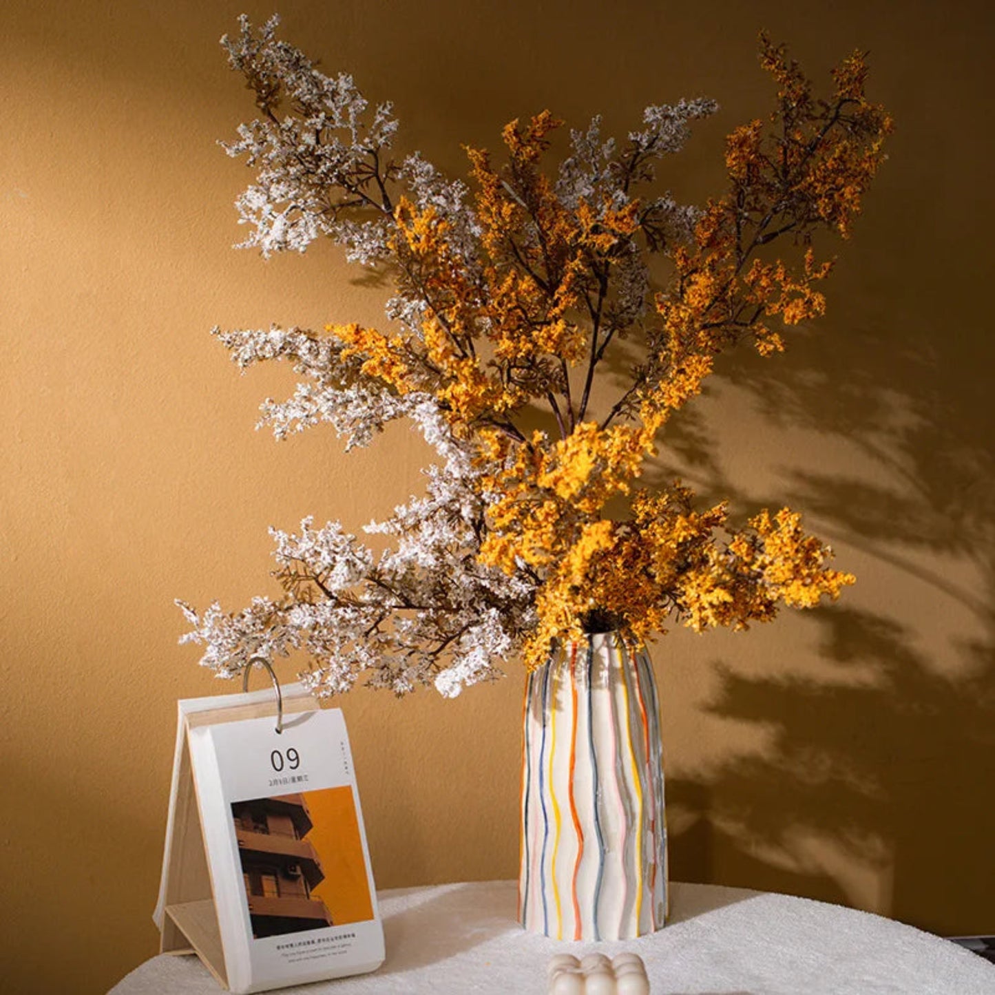 Decorative vase with dried flowers on a table against a brown wall