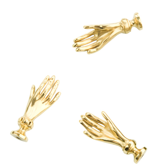 Gold hand-shaped cabinet handles on a white background.