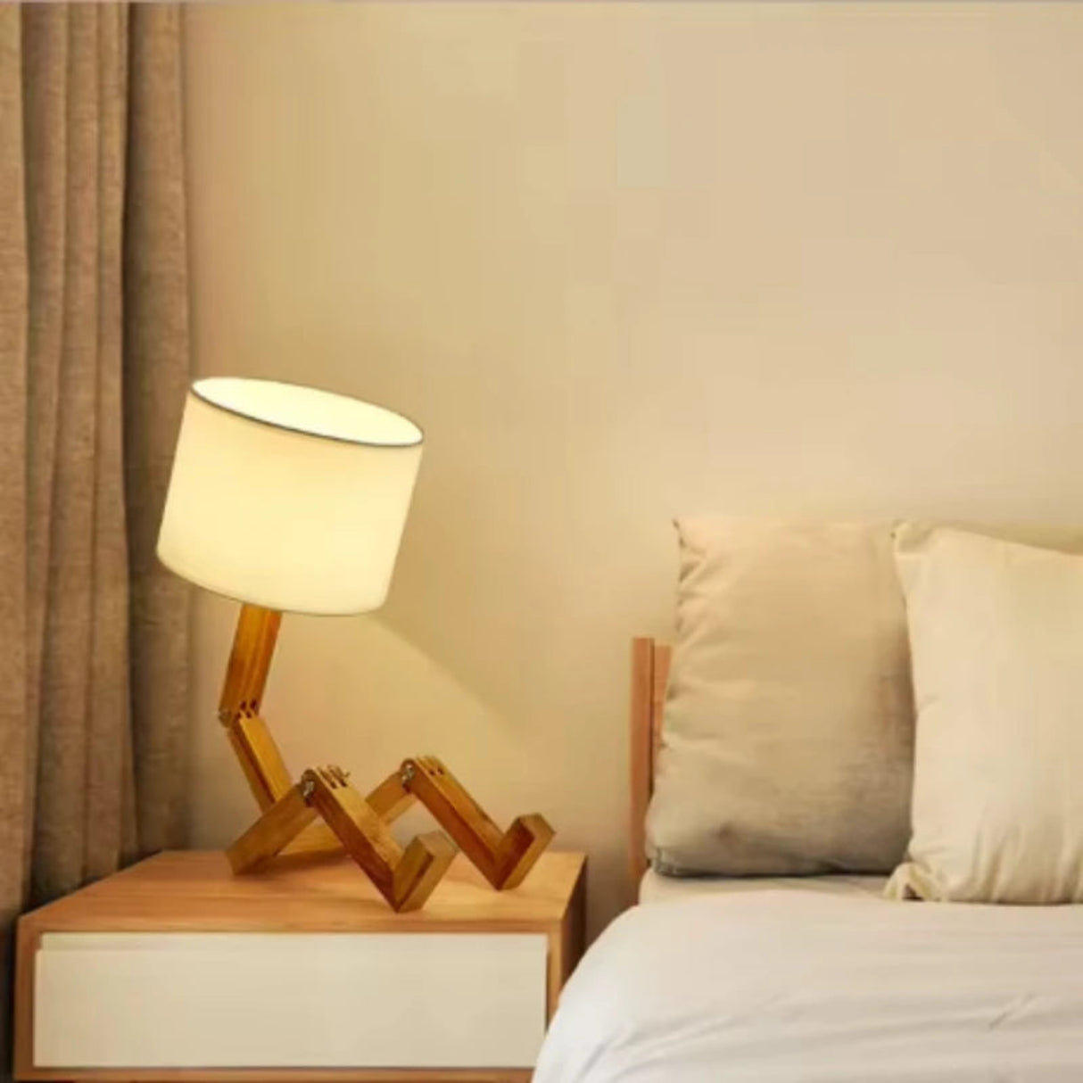 Wooden lamp on a nightstand next to a bed with pillows