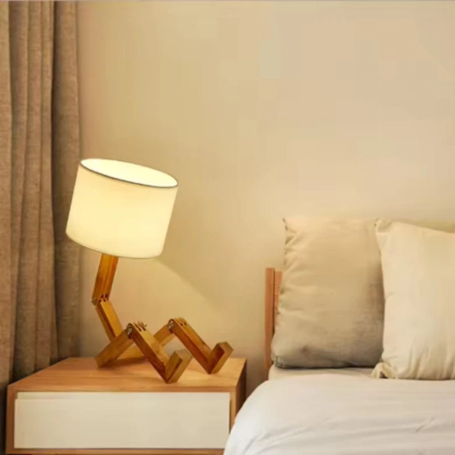 Wooden lamp on a nightstand next to a bed with pillows
