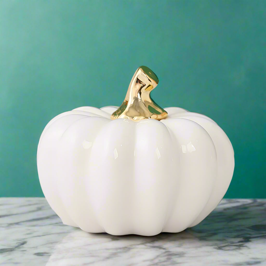 White ceramic pumpkin with a gold top on a marble surface