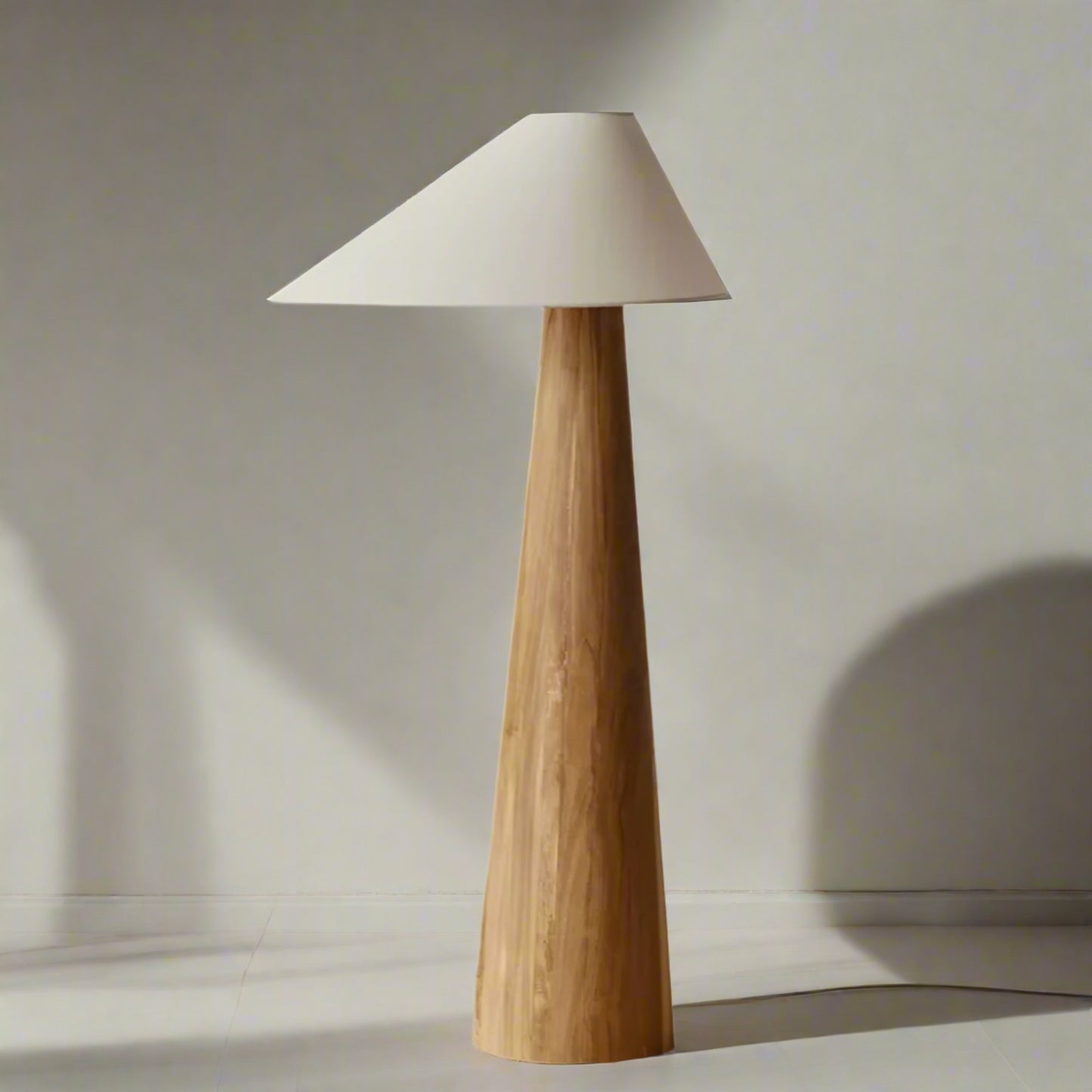 Floor lamp with wooden base and white conical shade on a textured surface.