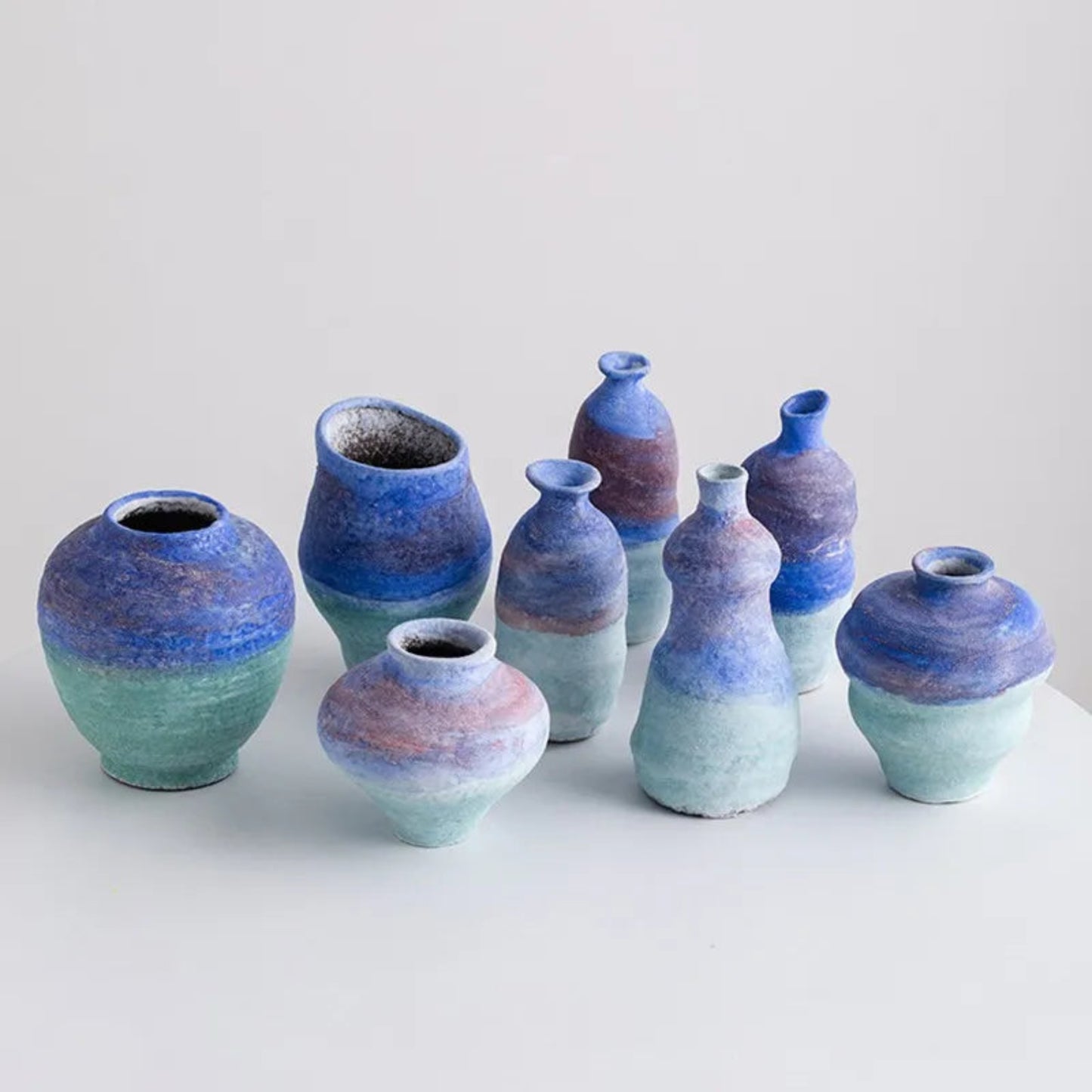 Set of ceramic vases with blue and green gradient on a light background