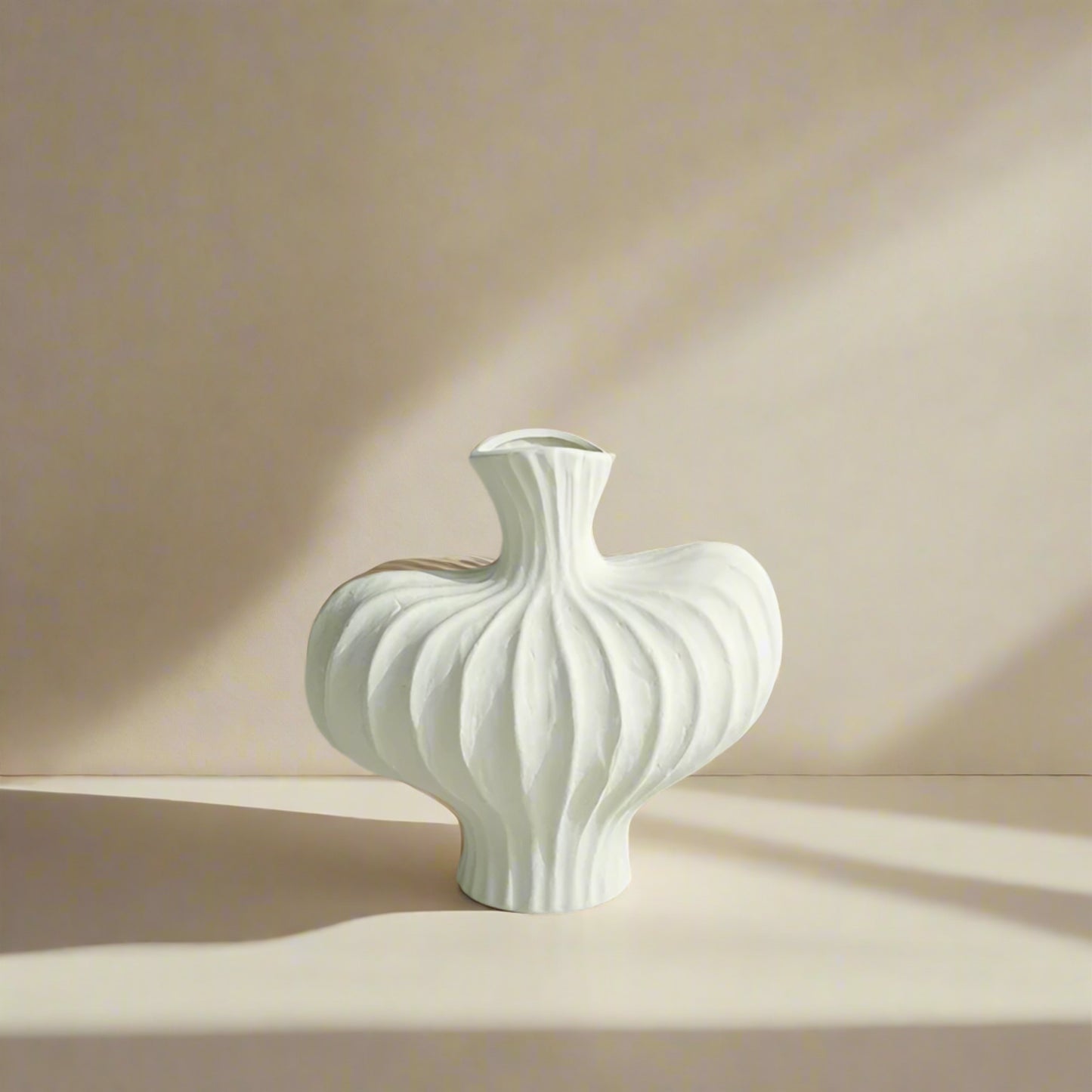 White textured vase on a light surface with a gray paneled wall background