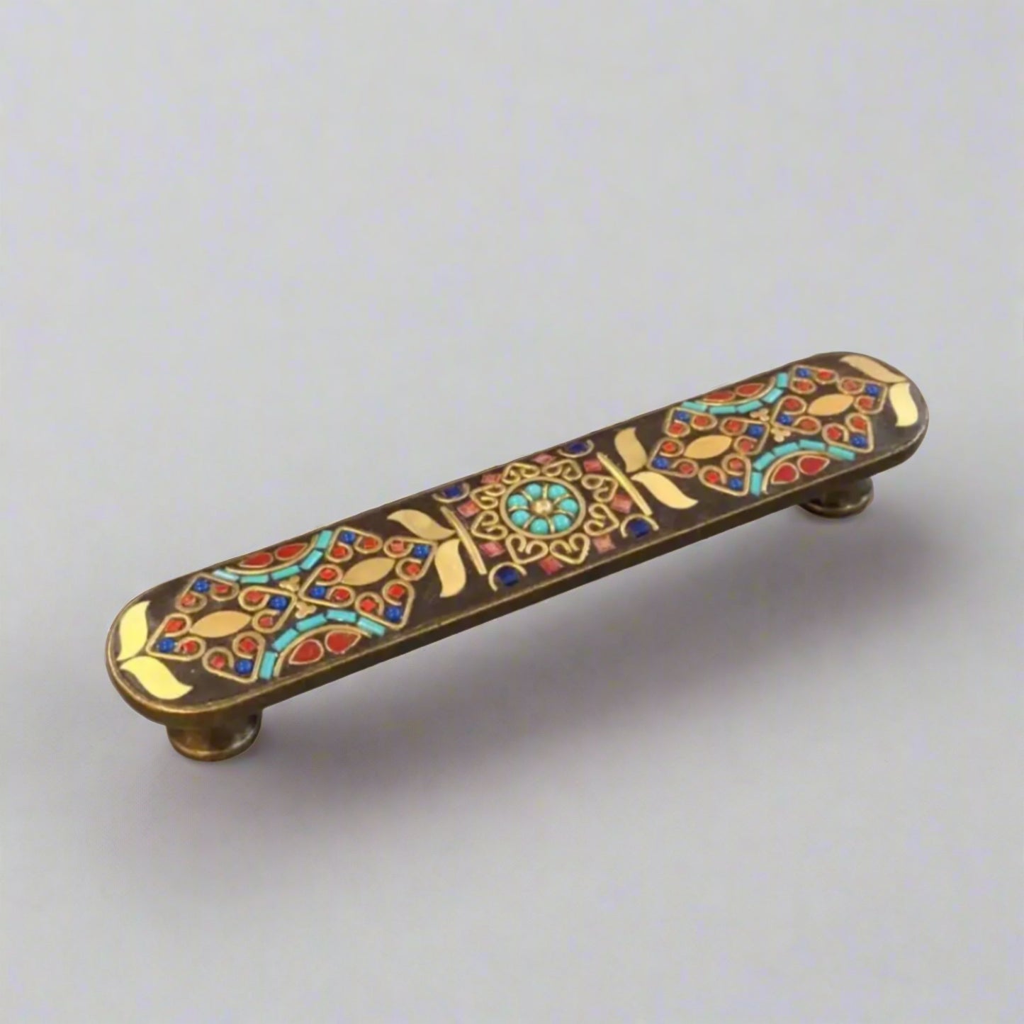 Decorative cabinet handle with colorful inlay on a gray background