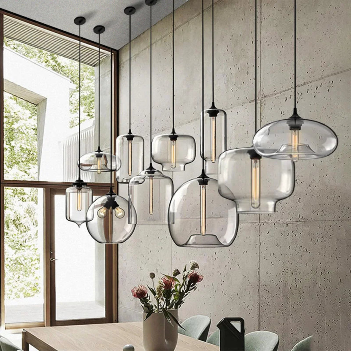 Modern pendant lights with glass shades in a room with a window and table.