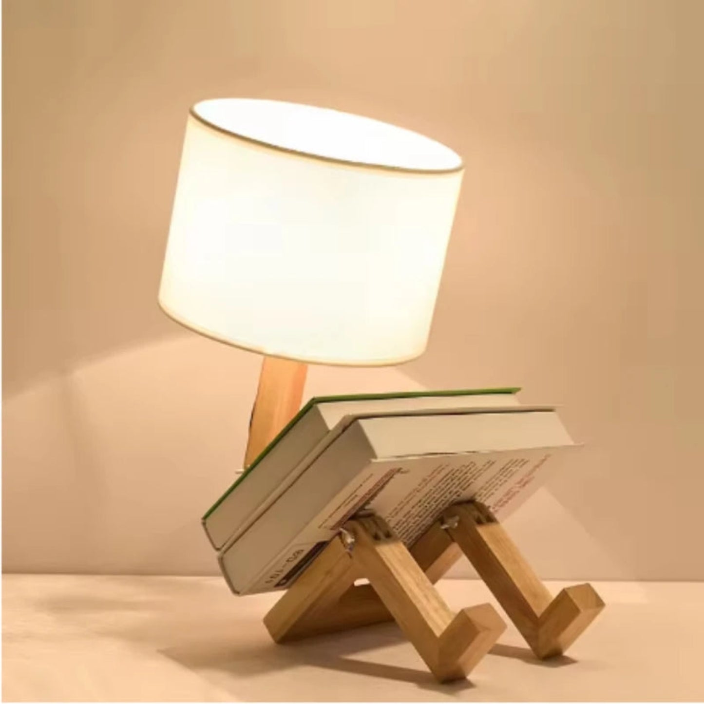 Small wooden lamp with a white shade on top of books against a beige background