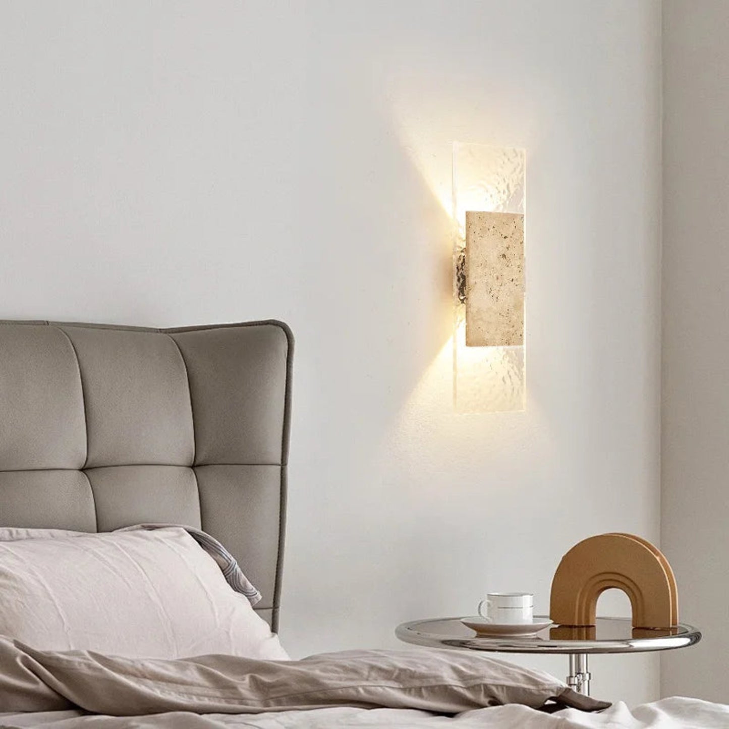 Modern bedroom with a bed, nightstand, and wall sconce.