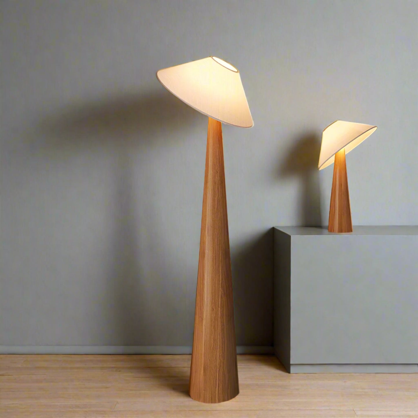 Wooden floor lamp and table lamp in a room setting with a neutral wall and wooden floor.