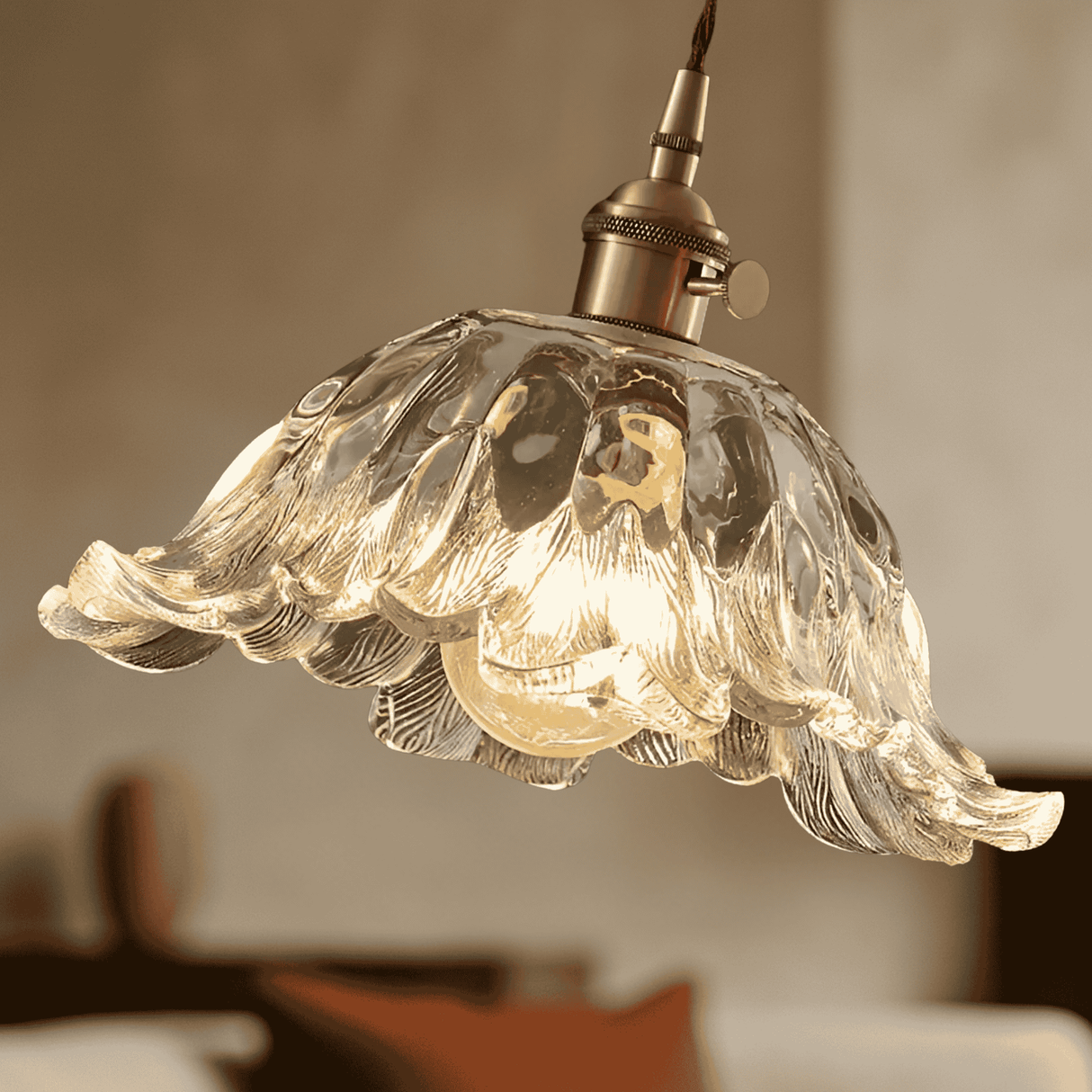 Decorative glass pendant light with a warm glow against a blurred background