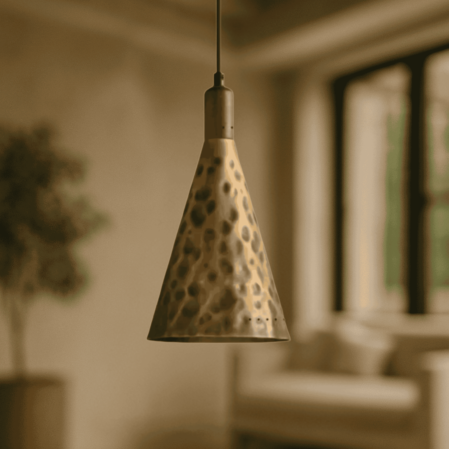 Conical pendant light with a spotted pattern hanging in a softly blurred room.