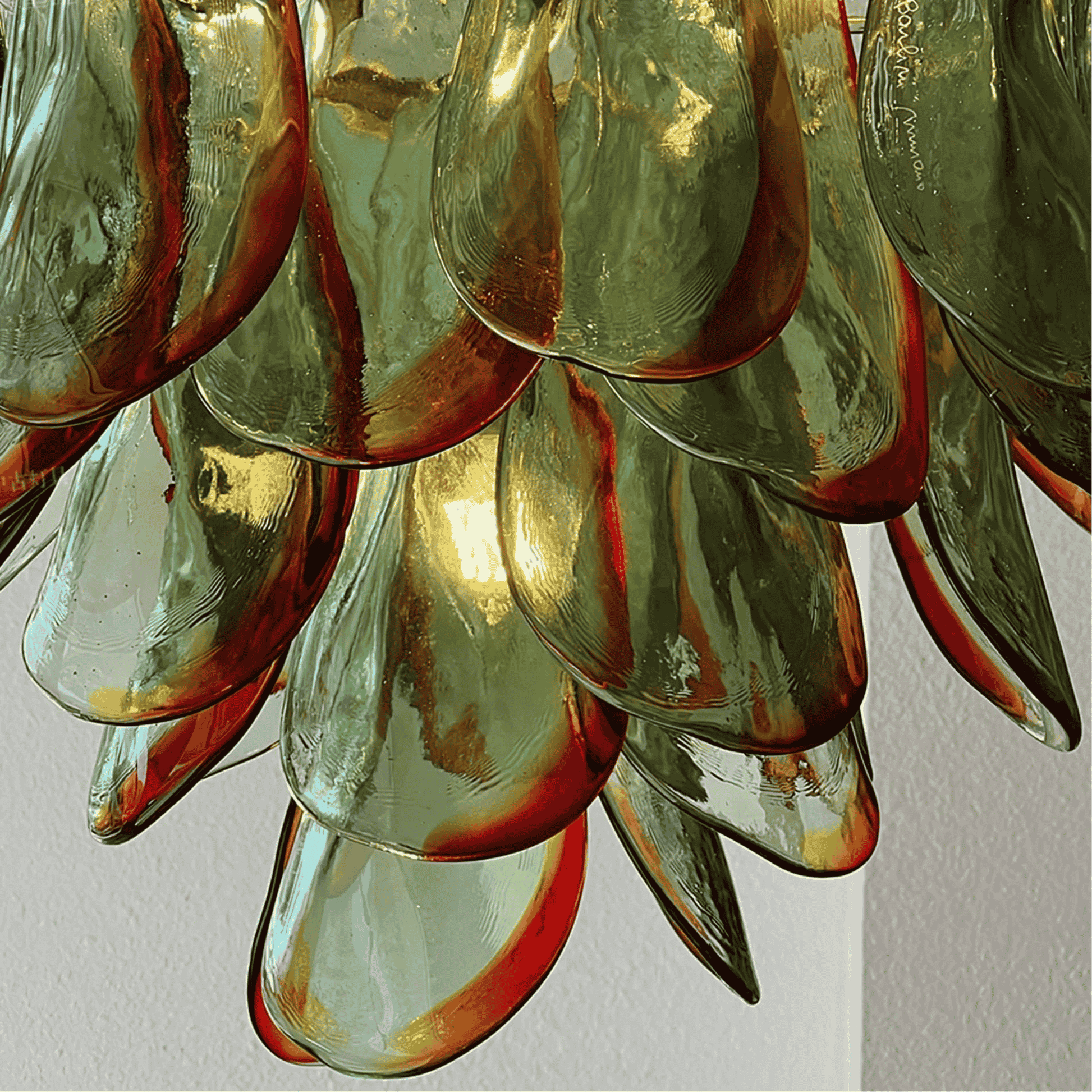 Close-up of a glass chandelier with green and red hues on a plain background