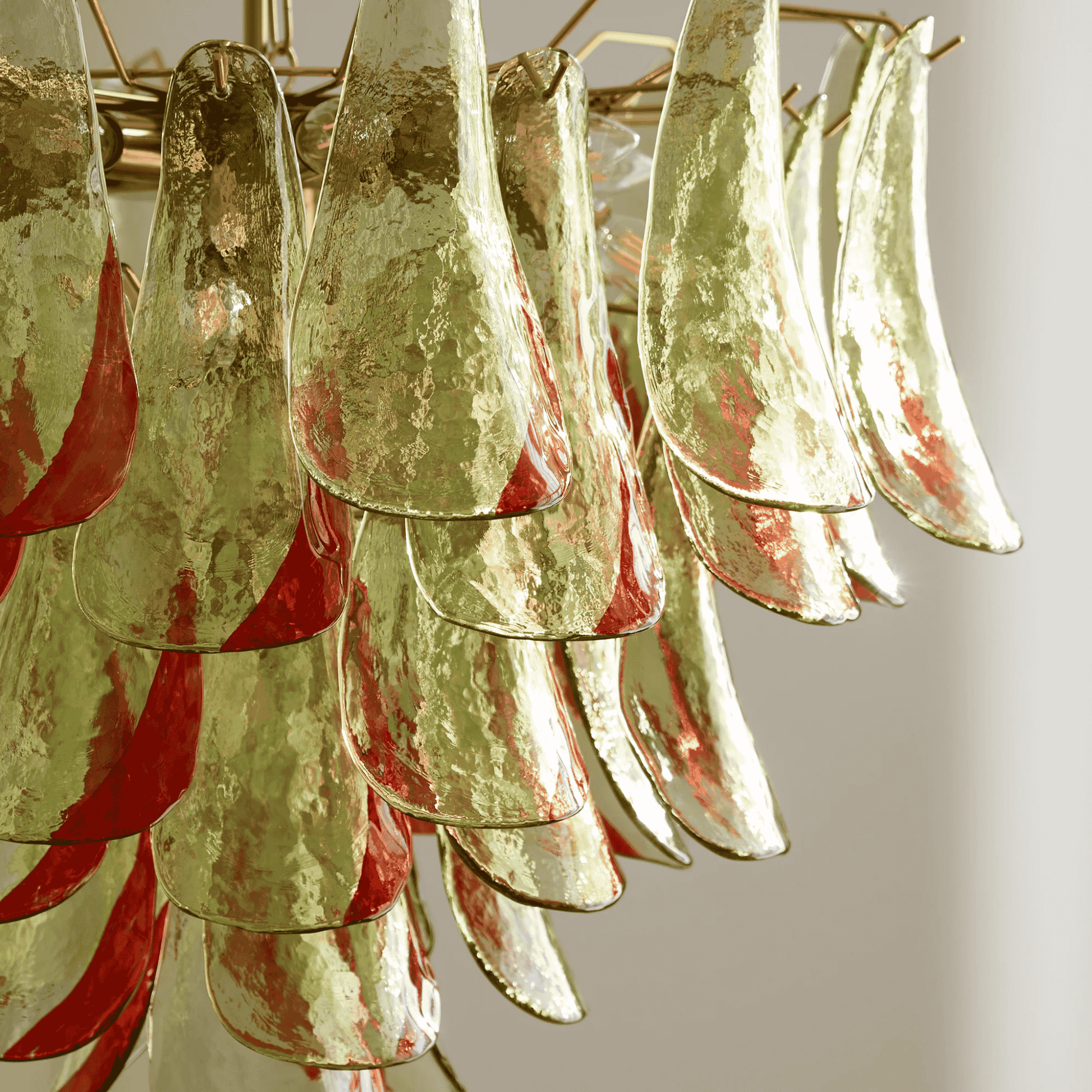 Close-up of a chandelier with gold and red glass shades on a neutral background