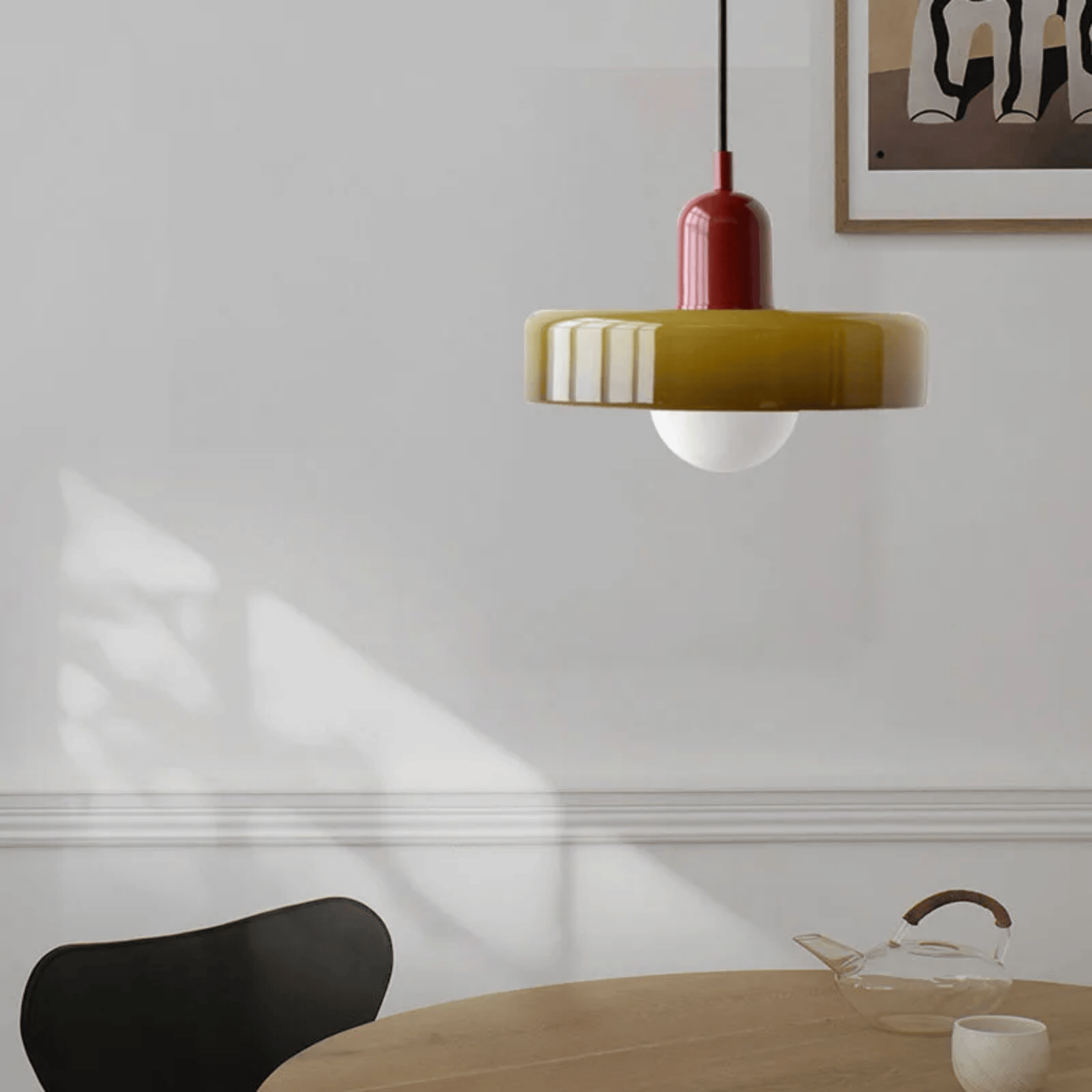 Modern pendant light hanging above a dining table with a minimalistic interior design.