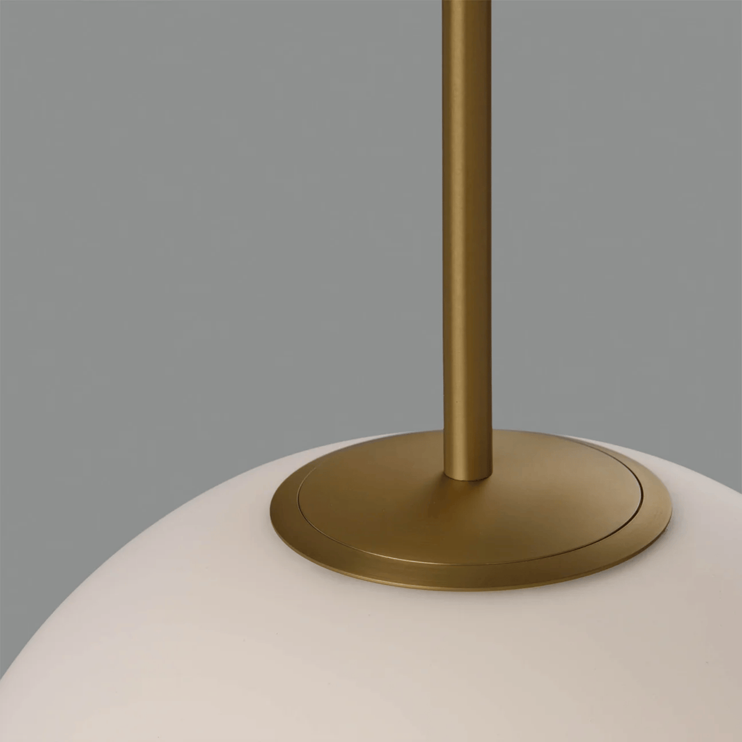 Close-up of a lamp with a gold base and white shade on a gray background