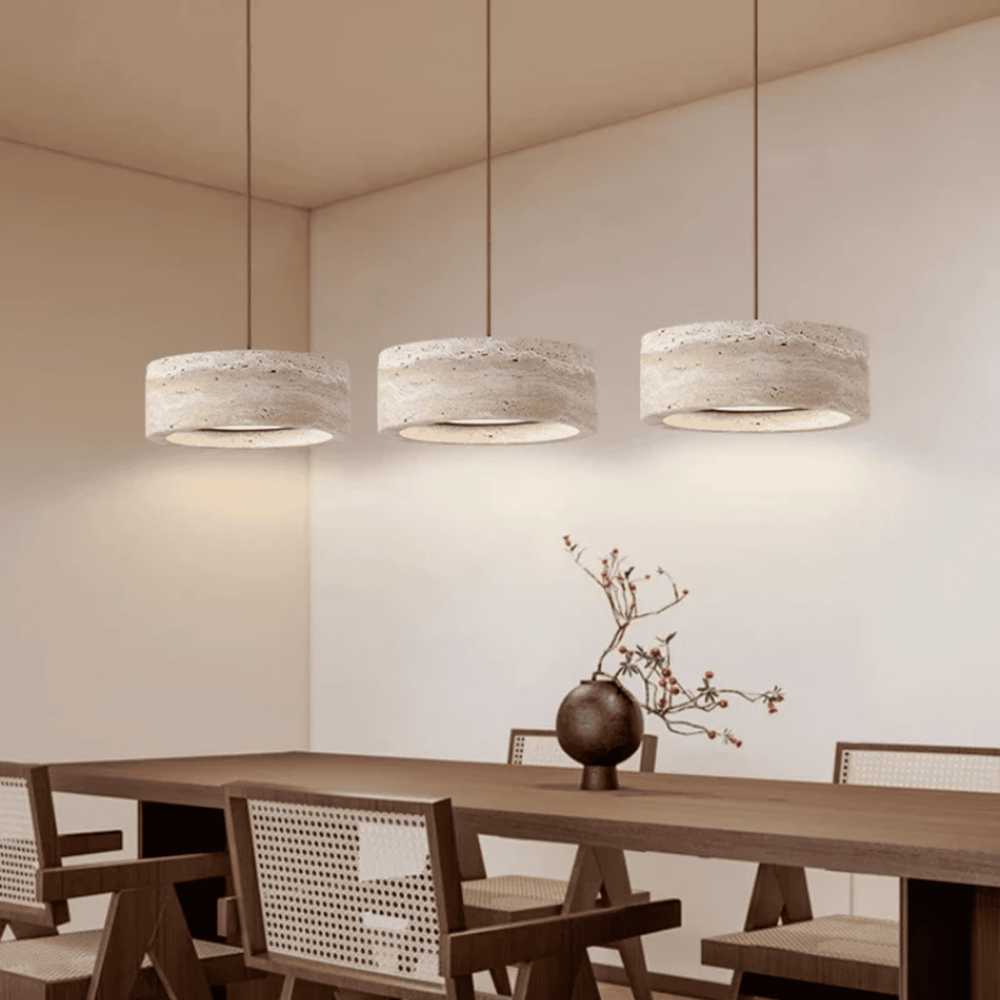 Three pendant lights hanging above a wooden dining table with chairs in a modern interior setting.