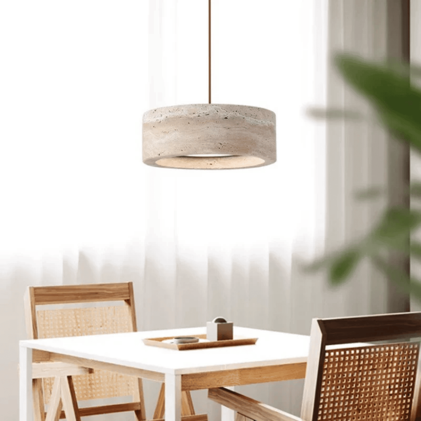 Dining area with a white table and wooden chairs, featuring a pendant light.