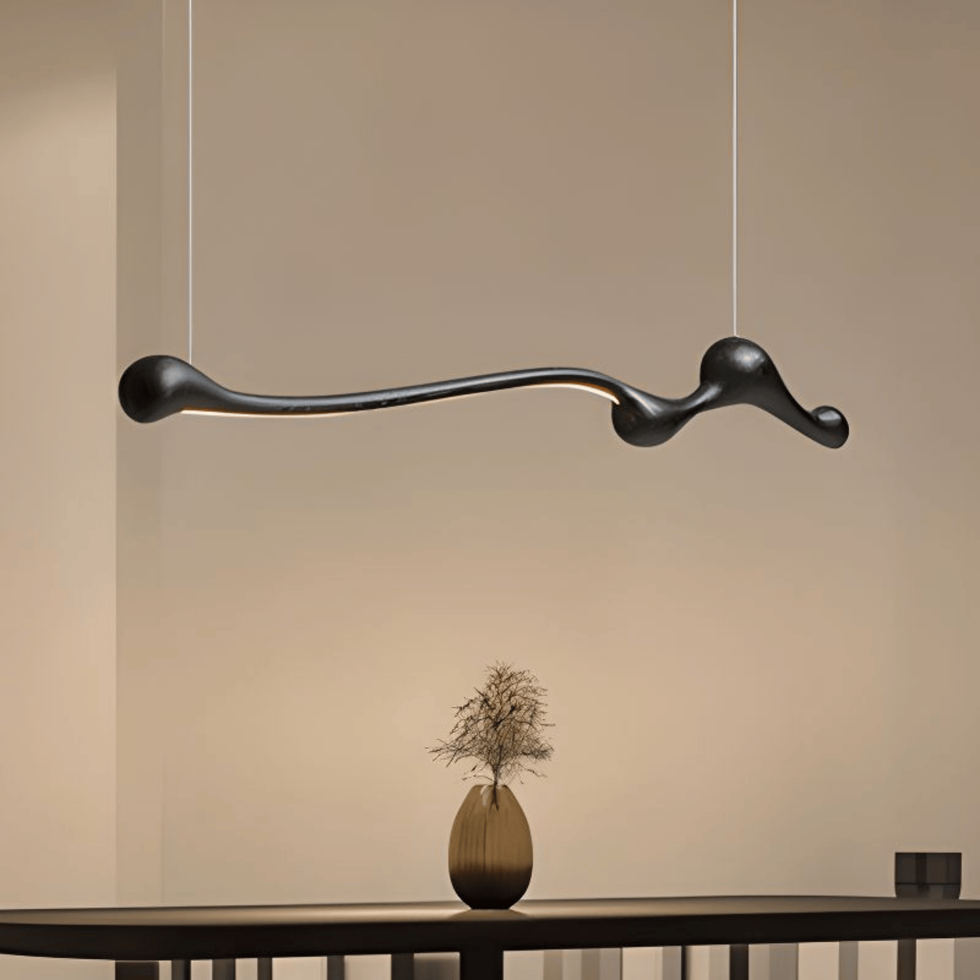 Modern black pendant light hanging above a table with a vase on a neutral background