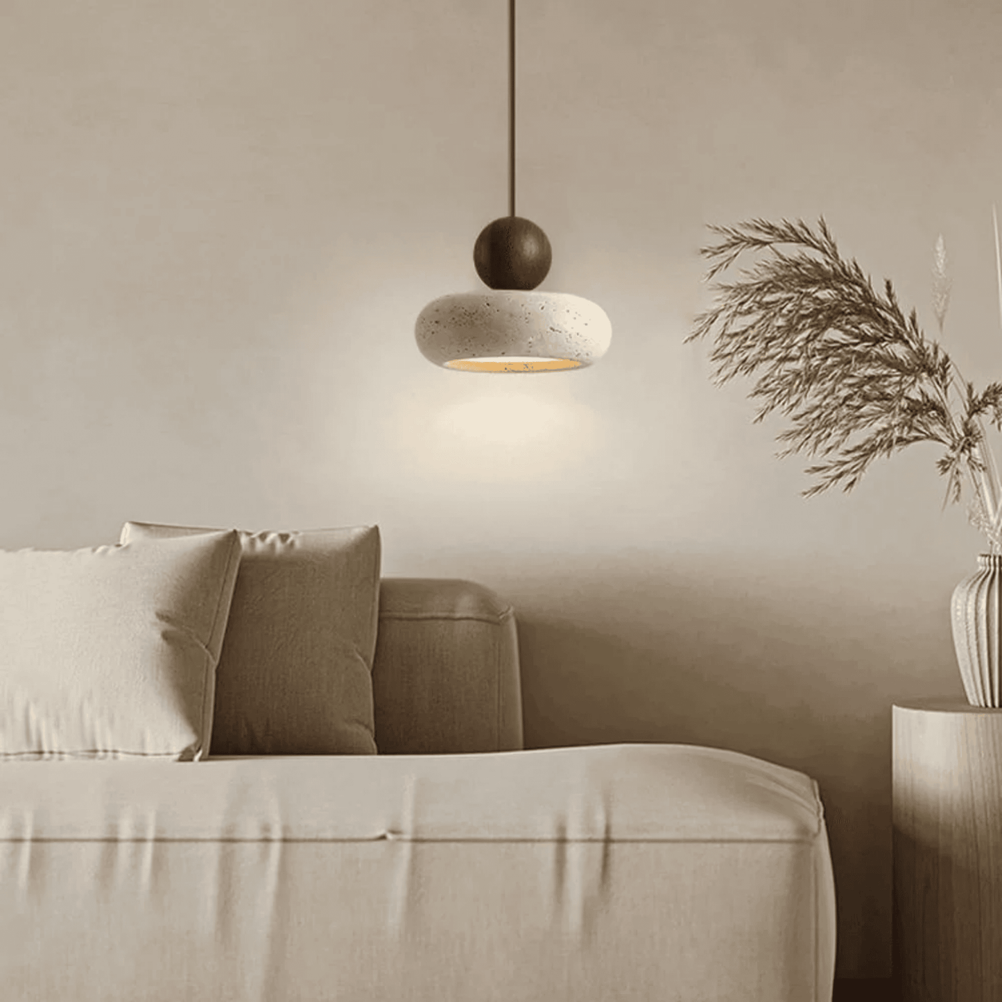 Modern living room with a beige sofa, pendant light, and decorative plant.