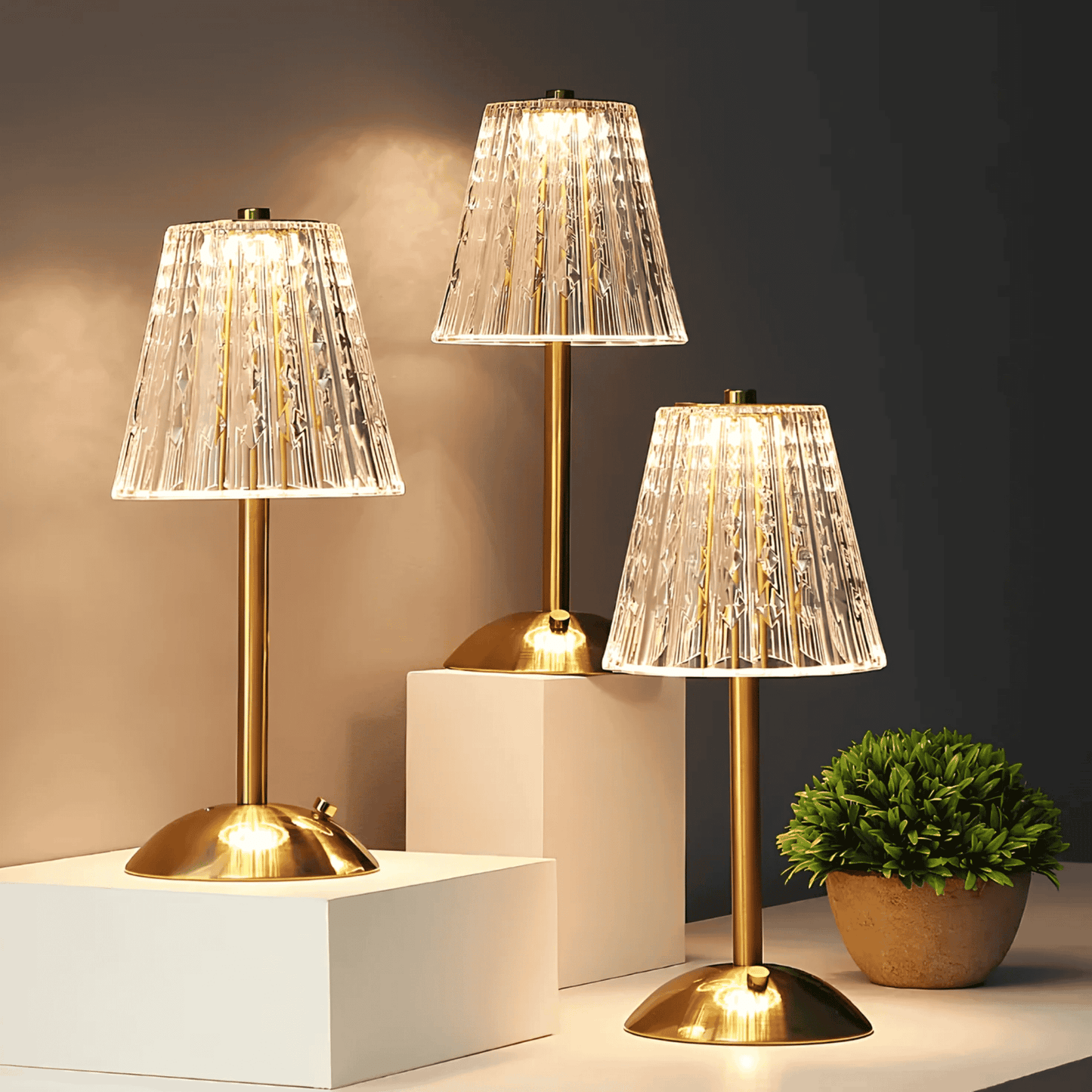 Three table lamps with gold bases and clear glass shades on a dark background.