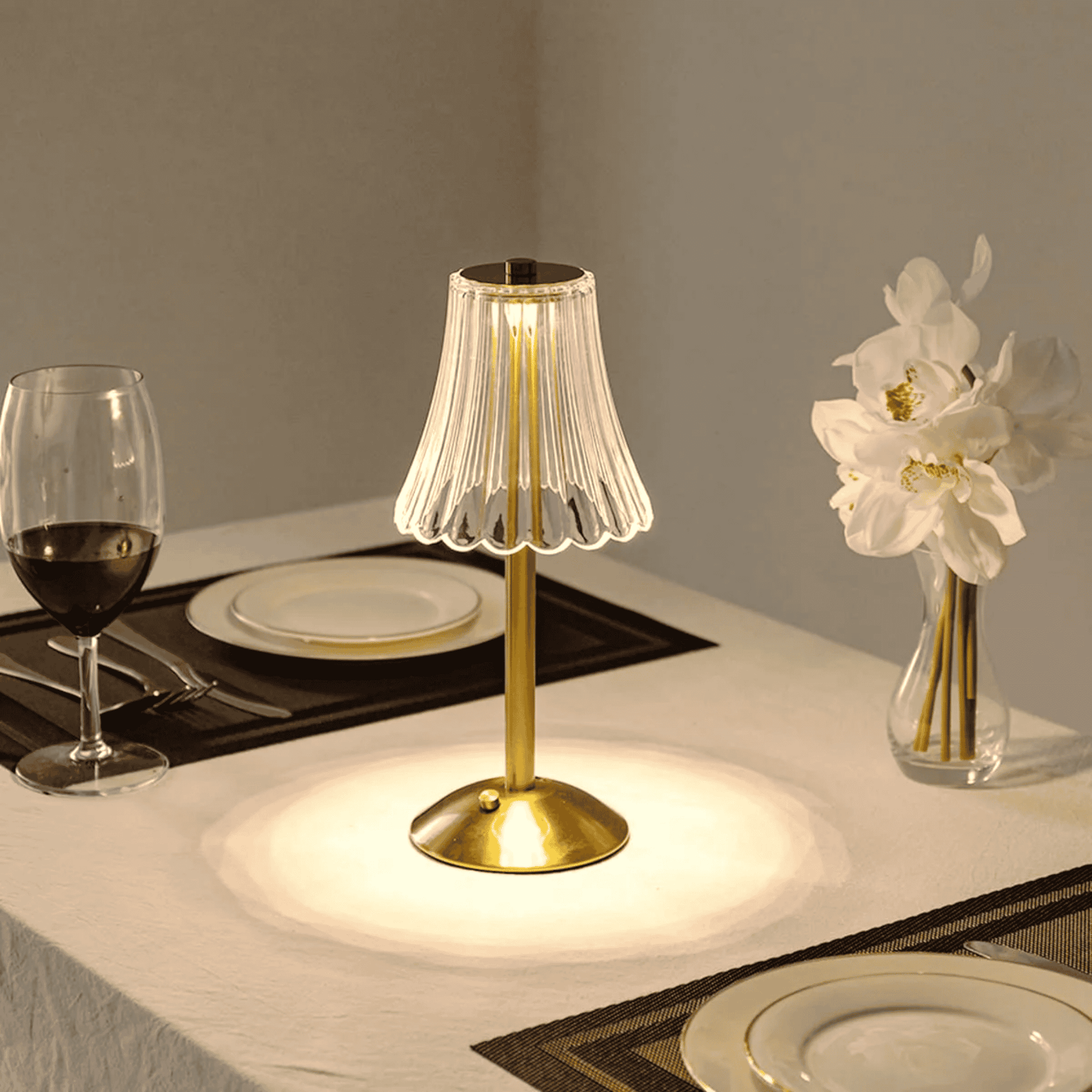 Gold table lamp on a dining table with wine glass and plates