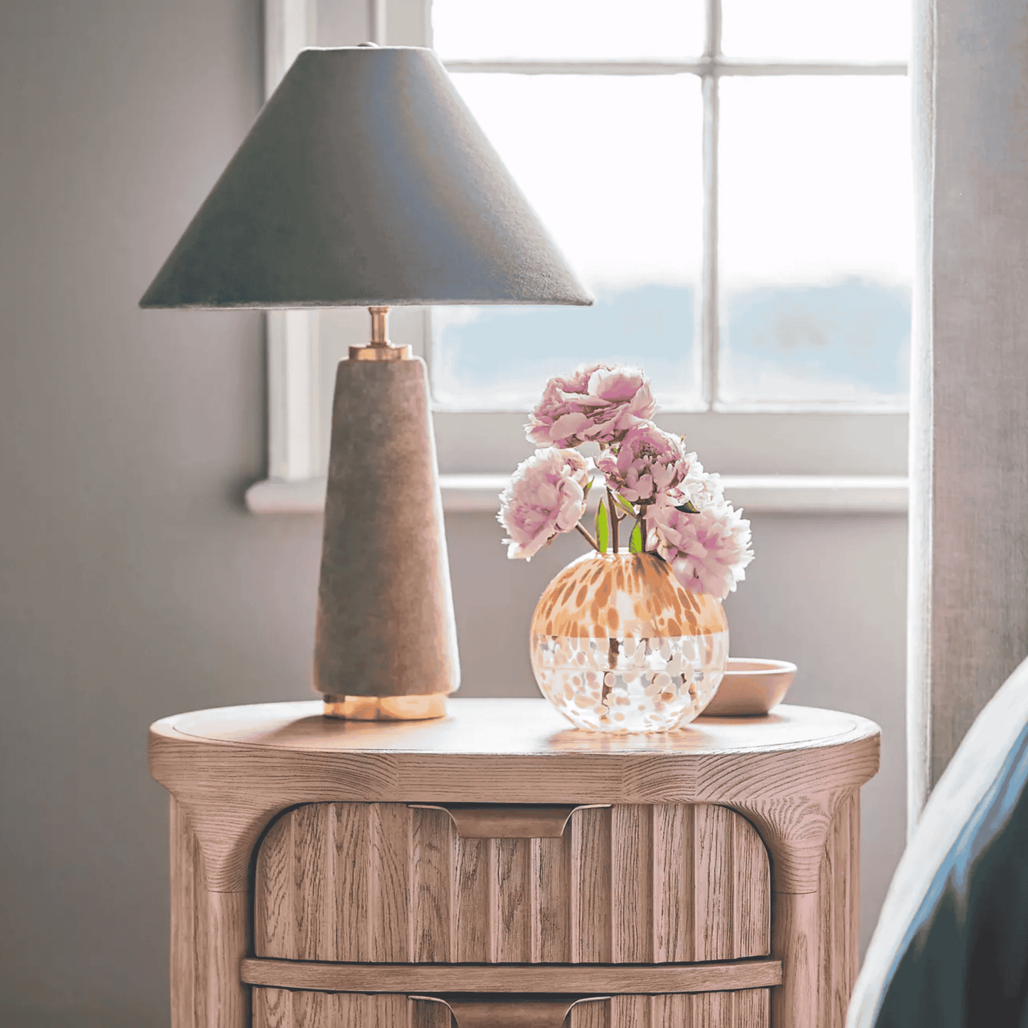 Table lamp and decorative items on a wooden side table by a window