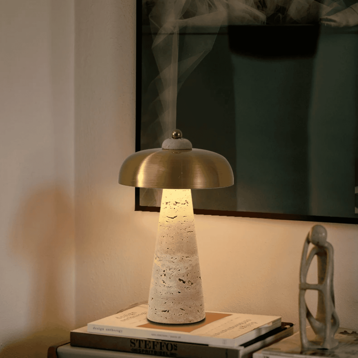 Table lamp with a textured base and gold shade on a stack of books, with a blurred background.