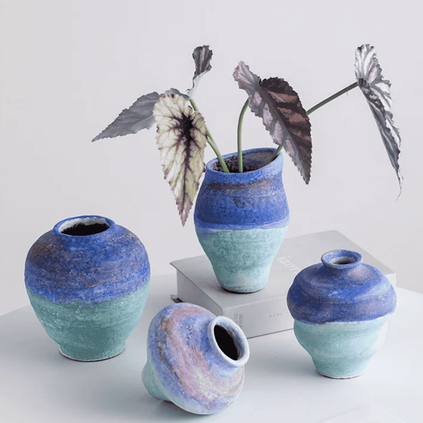 Set of ceramic vases with a gradient blue and green finish on a light background.