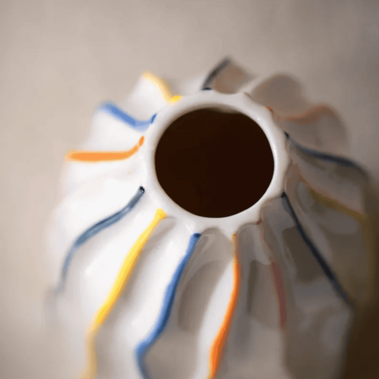 Close-up of a ceramic vase with colorful stripes on a neutral background
