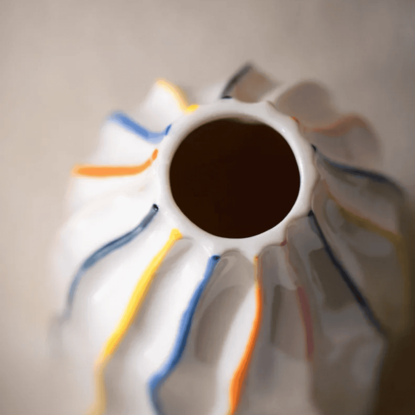 Close-up of a ceramic vase with colorful stripes on a neutral background