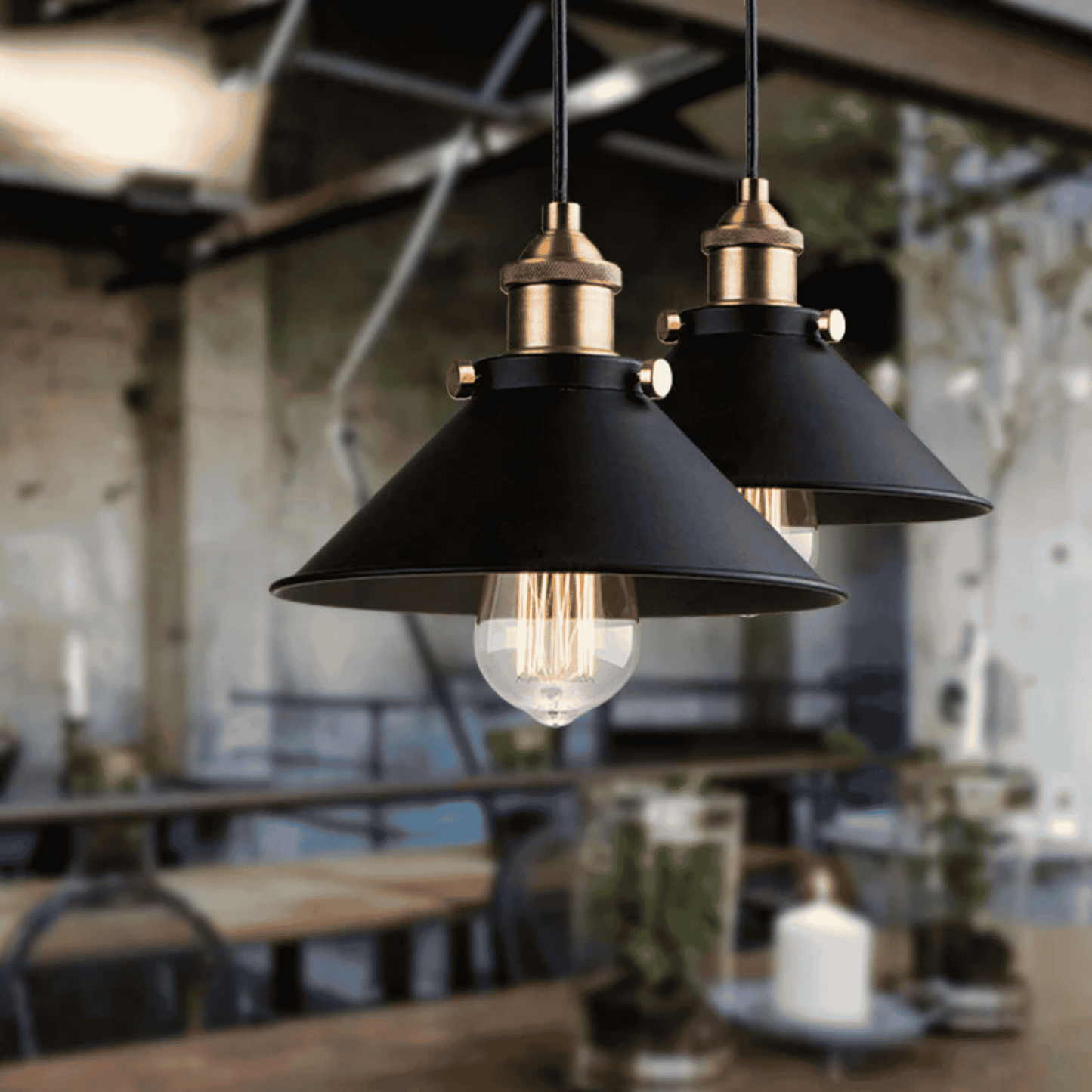 Two black pendant lights with gold accents hanging in a blurred indoor setting.