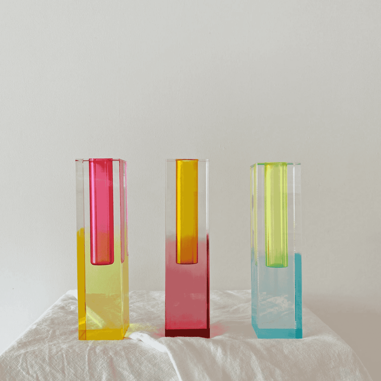 Three colorful glass vases on a white surface with a light gray background