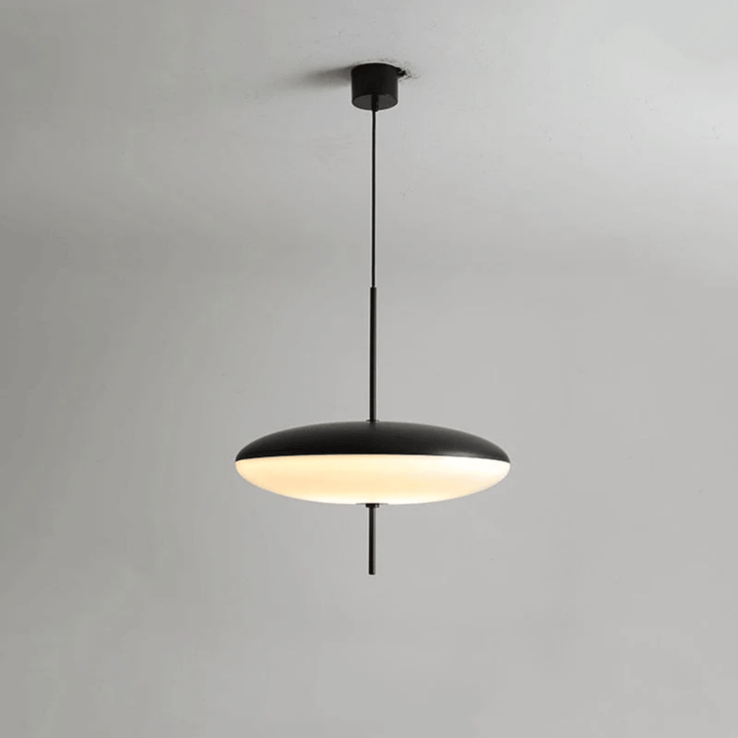 Modern pendant light with black fixture and white shade on a gray background