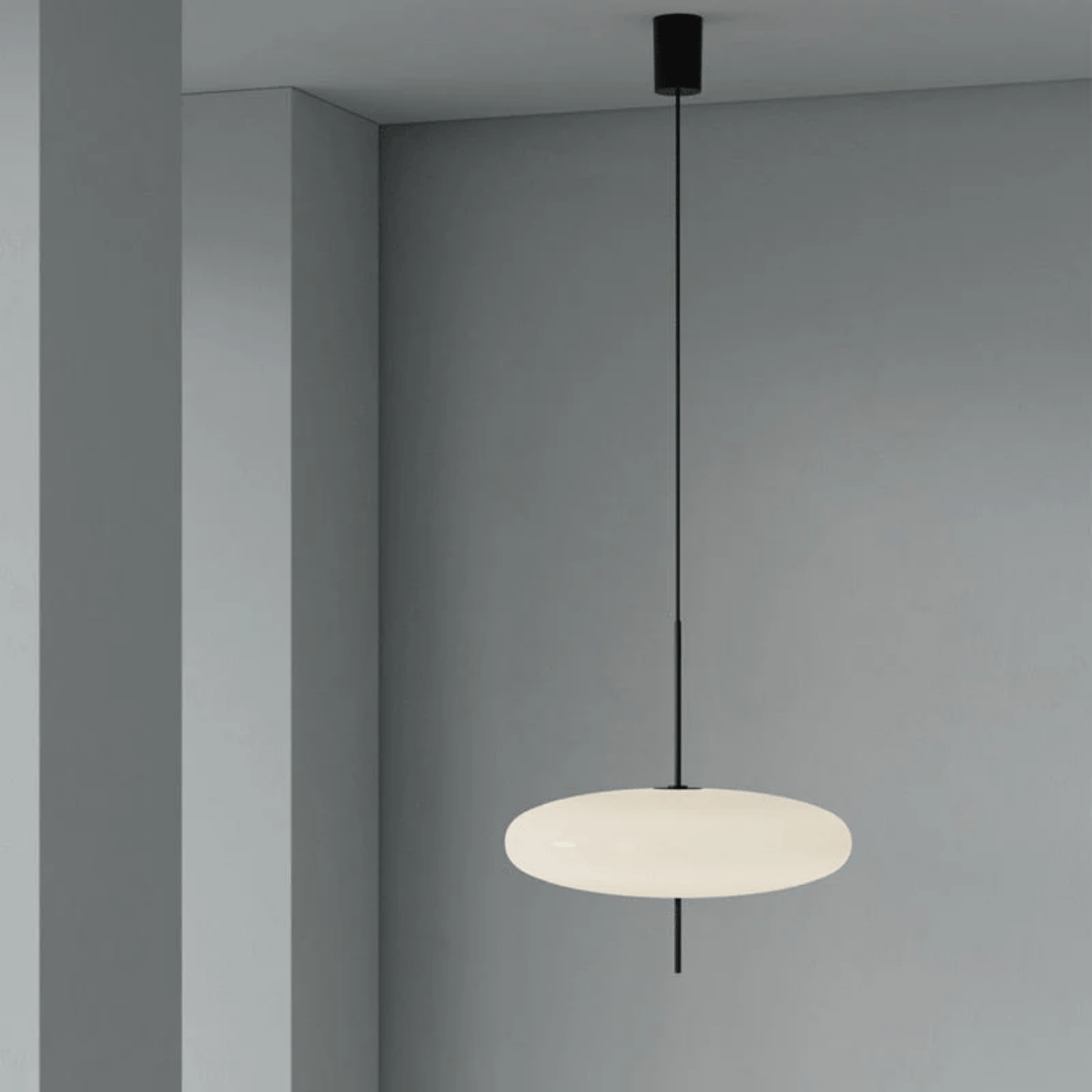 Modern pendant light hanging against a gray wall