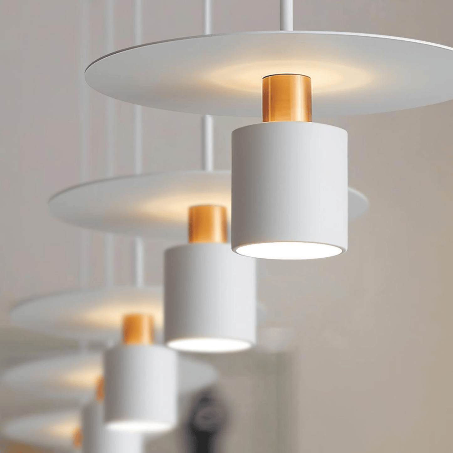Modern pendant light fixture with white and gold components on a neutral background
