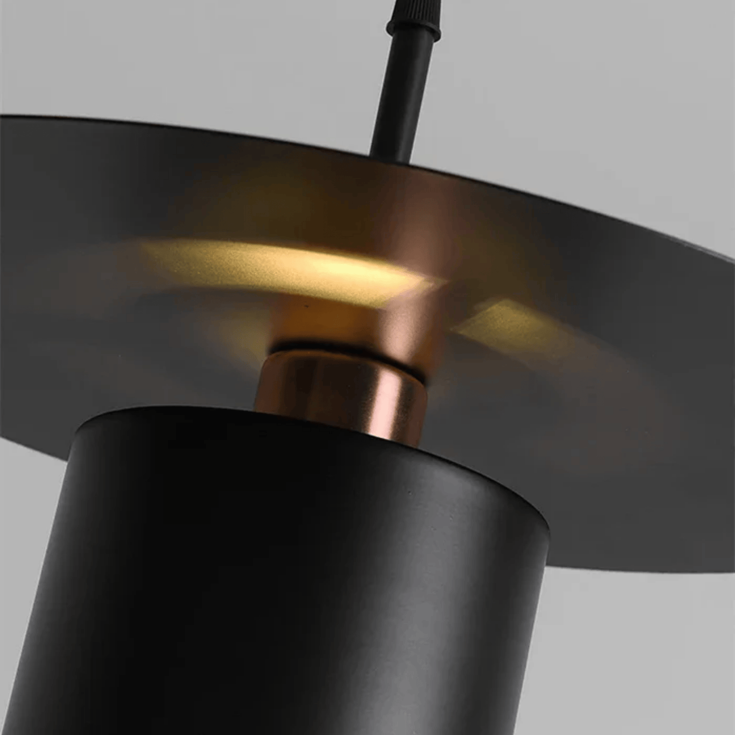 Close-up of a black and copper pendant light fixture against a gray background