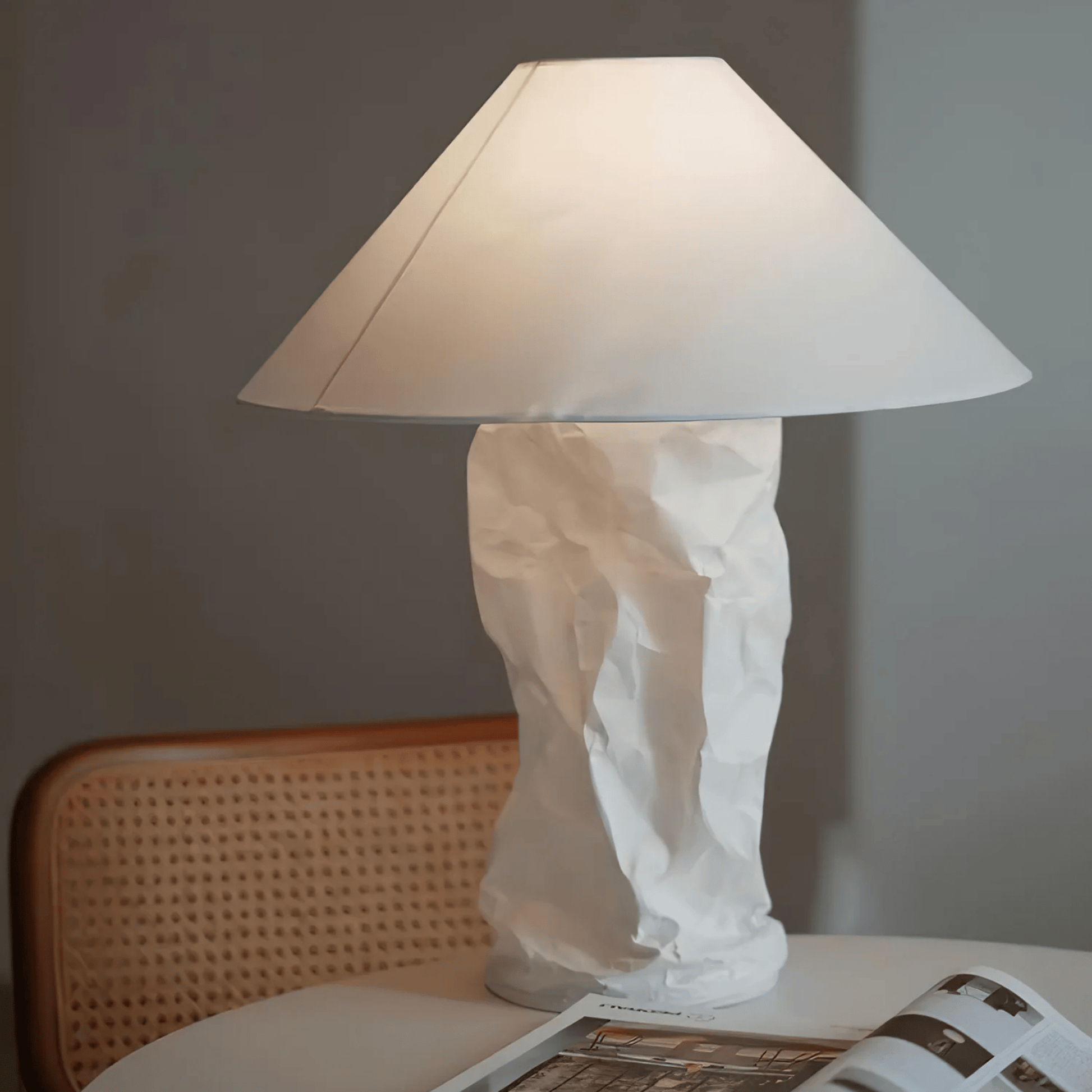 White lamp with a textured base on a table next to a chair.