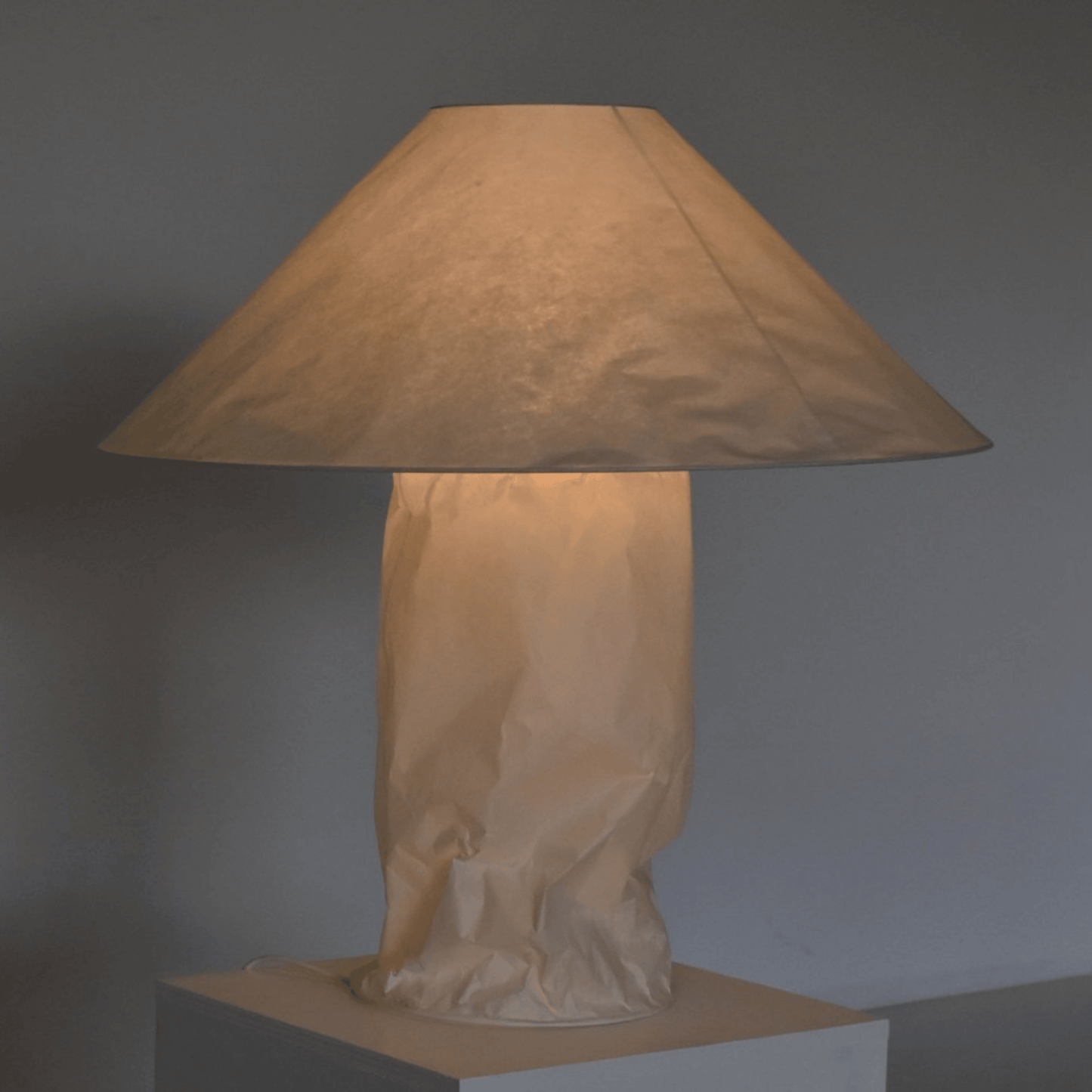 Table lamp with a beige paper bag base against a gray background