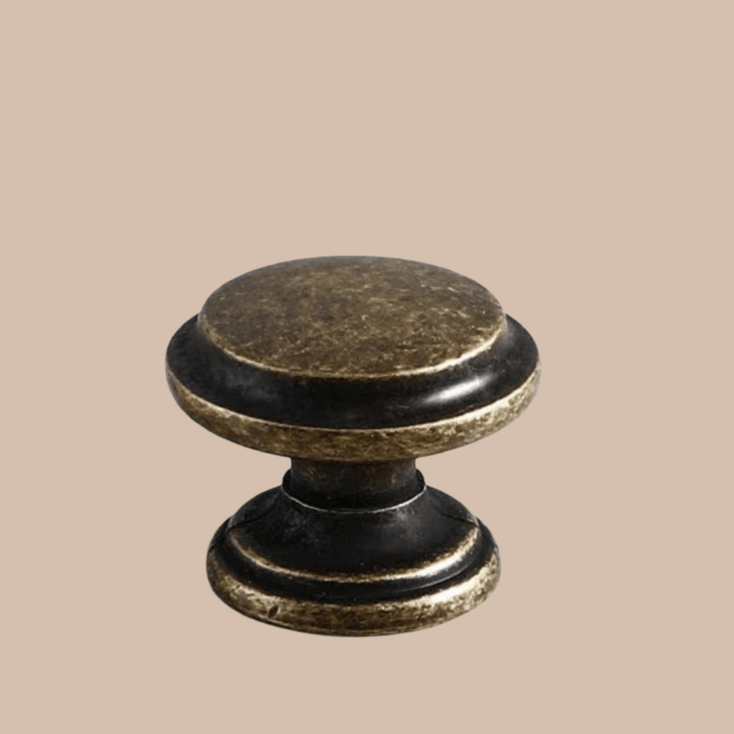 Decorative cabinet knob with black and gold finish on a beige background