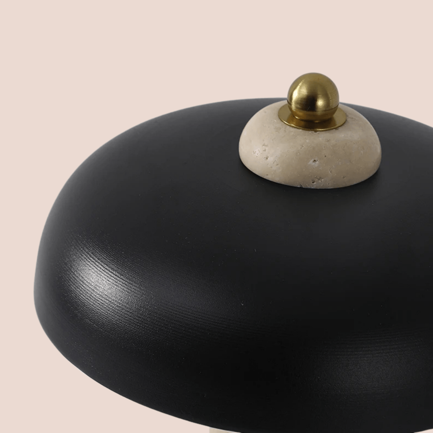 Black ceramic dish with a gold and white decorative element on a beige background