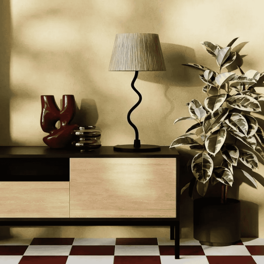 Modern sideboard with a lamp, decorative items, and a plant against a beige wall.