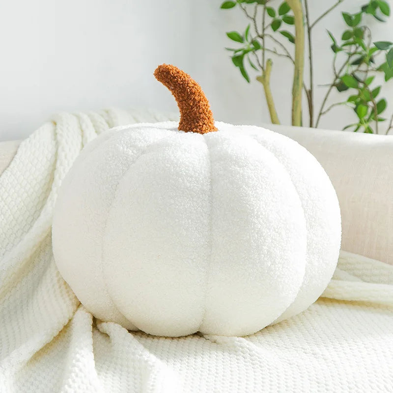 White pumpkin-shaped pillow with a brown stem on a white surface
