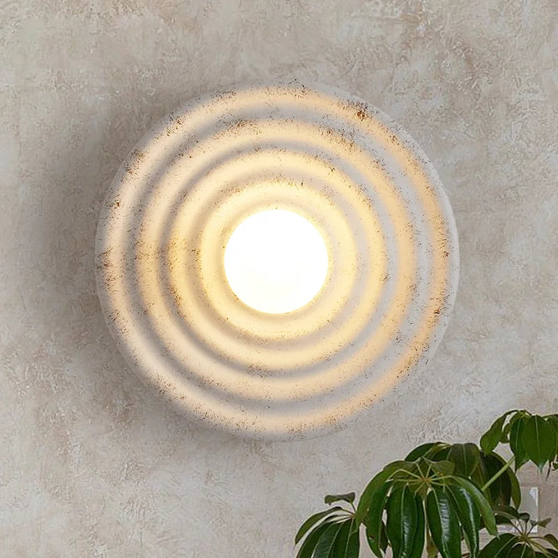 Round wall light fixture with concentric circles on a textured wall