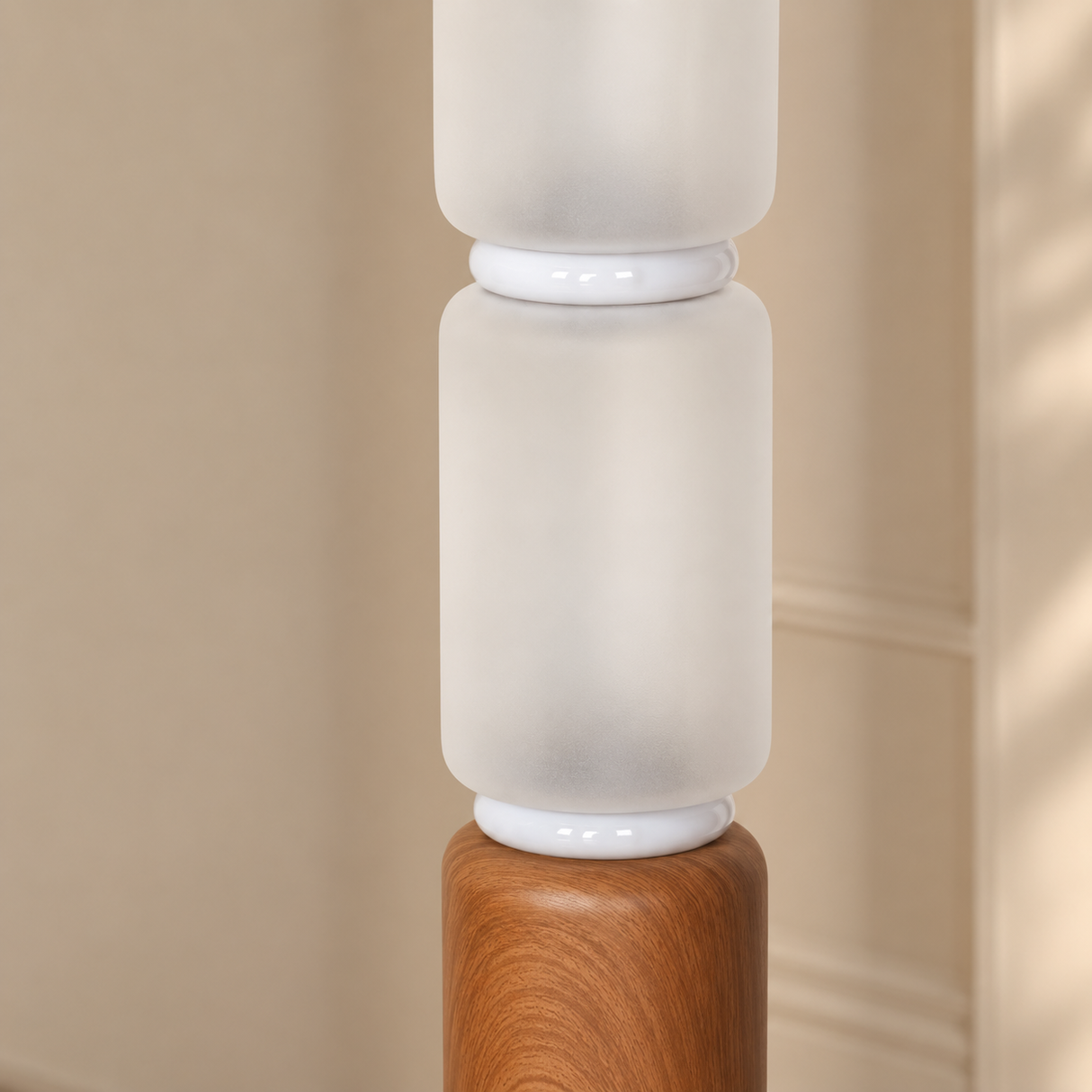 A close-up of a modern floor lamp featuring frosted white cylindrical glass shades stacked vertically on a warm medium-brown wood base, set against a softly blurred beige interior wall.