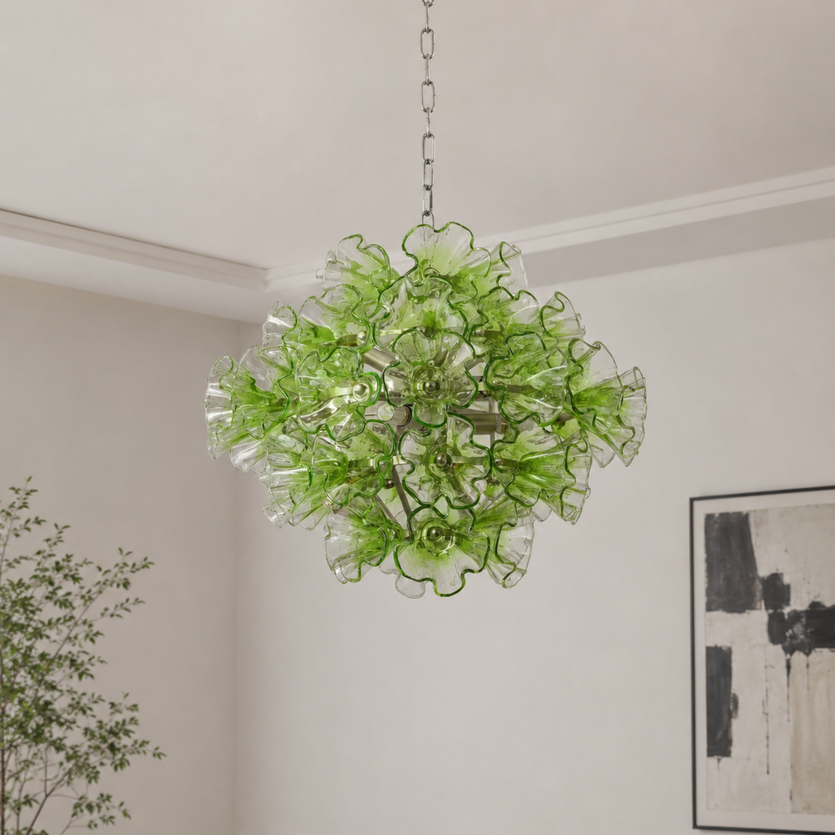 Green floral chandelier hanging in a room with a plant and artwork on the wall.