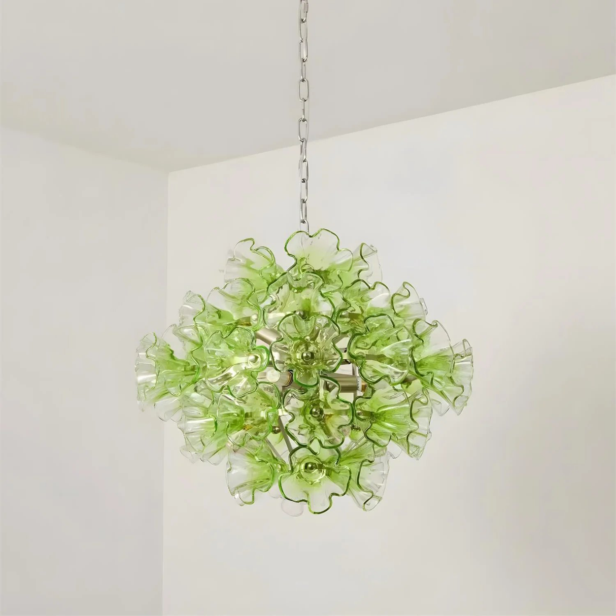 Green floral chandelier hanging against a white wall
