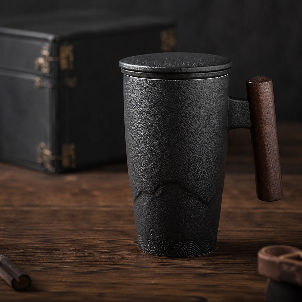 Kuro Artisan Ceramic Tea Infuser Mug in charcoal ceramic with wooden handle on a warm timber table