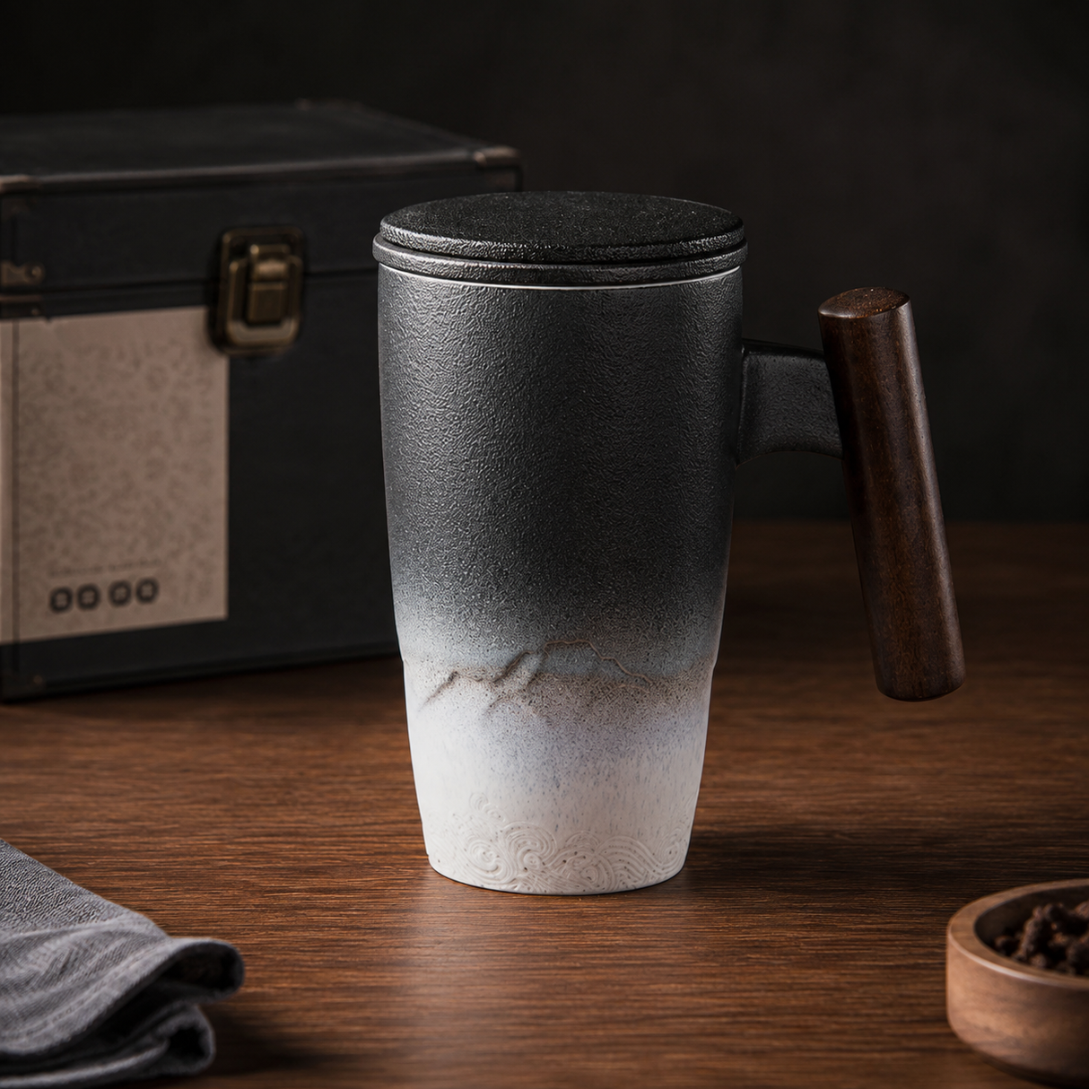 Kuro Artisan Ceramic Tea Infuser Mug in charcoal and white glaze with wooden handle on a warm timber table