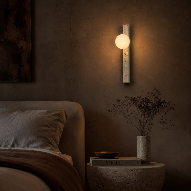 Modern wall sconce in a dimly lit bedroom setting with a bed and decorative items.